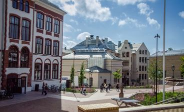 en gruppe mennesker som går rundt på en gårdsplass foran en bygning