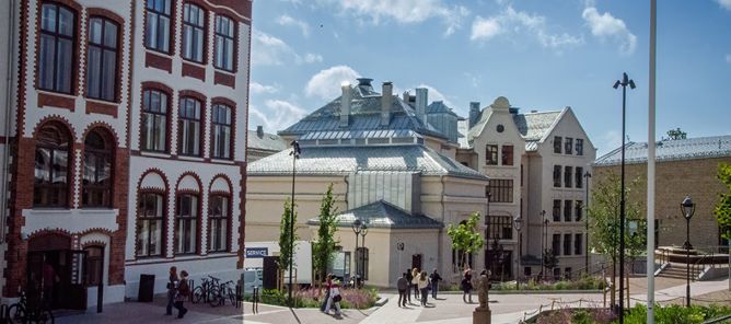 en gruppe mennesker som går rundt på en gårdsplass foran en bygning