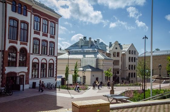 en gruppe mennesker som går rundt på en gårdsplass foran en bygning