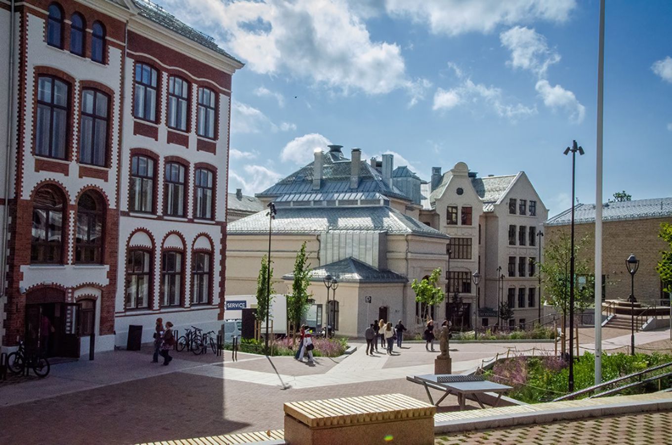 en gruppe mennesker som går rundt på en gårdsplass foran en bygning