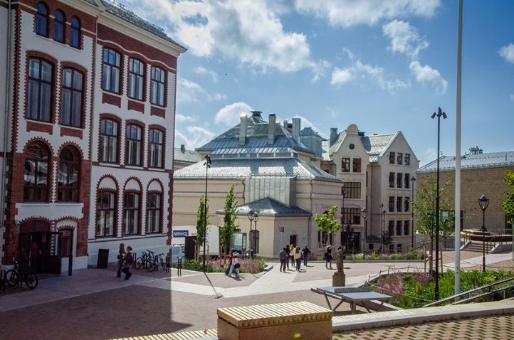 en gruppe mennesker som går rundt på en gårdsplass foran en bygning